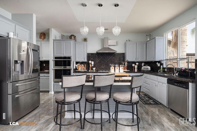11703 Revolution Rd, Bakersfield, CA 93312 - kitchen with stainless steel appliances, wall chimney range hood, a kitchen bar, backsplash, and pendant lighting
