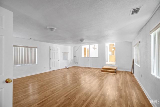 unfurnished living room featuring plenty of natural light, hardwood / wood-style floors, and a textured ceiling