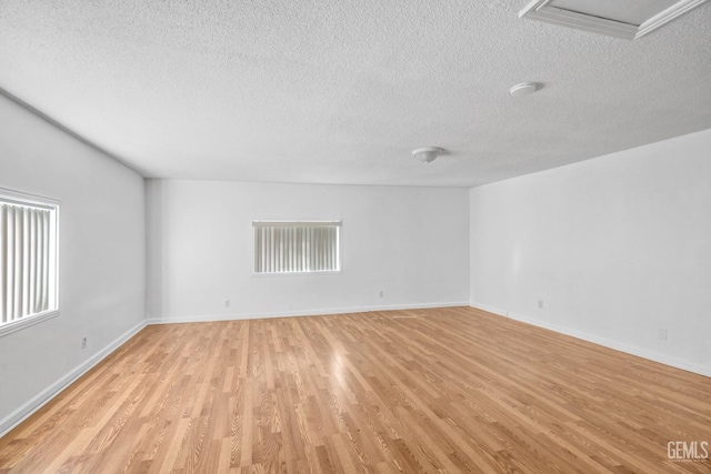 spare room featuring a textured ceiling and light hardwood / wood-style flooring