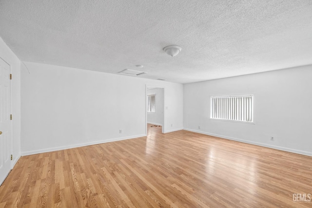 empty room with a textured ceiling and light hardwood / wood-style floors