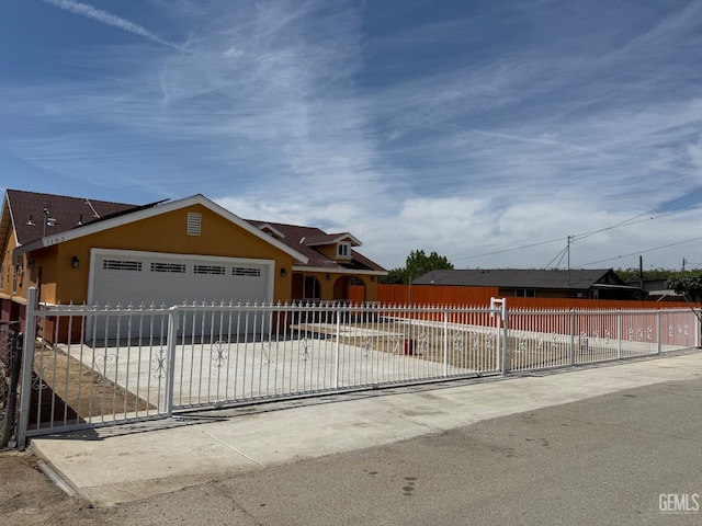 view of front facade featuring fence private yard, a garage, stucco siding, and concrete driveway