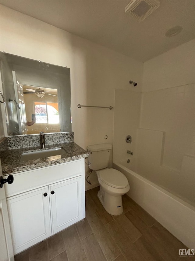 bathroom with a ceiling fan, bathtub / shower combination, wood finished floors, vanity, and toilet