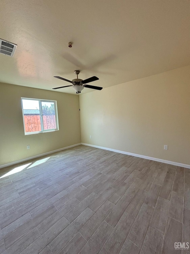 unfurnished room with baseboards, ceiling fan, wood finished floors, and visible vents