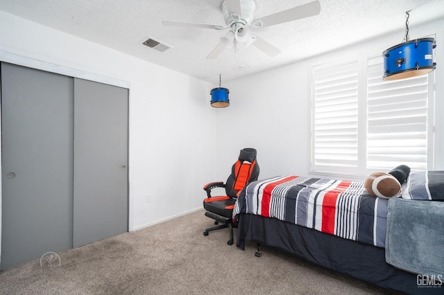 bedroom featuring ceiling fan, a closet, carpet, and a textured ceiling