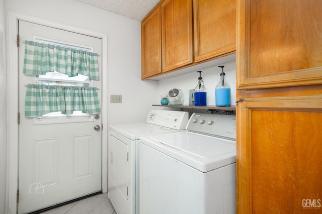 laundry area featuring cabinets, light tile patterned floors, a textured ceiling, and independent washer and dryer