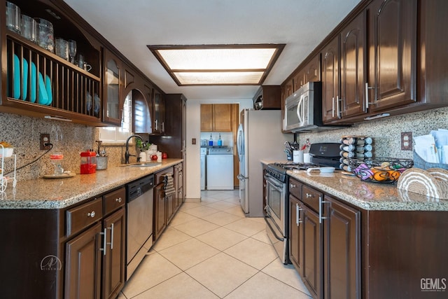 kitchen featuring dark brown cabinetry, appliances with stainless steel finishes, washer / dryer, and sink