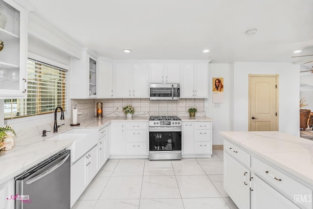 kitchen with appliances with stainless steel finishes, a sink, white cabinets, and decorative backsplash