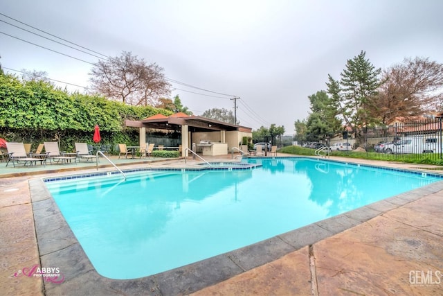 community pool with a patio area, fence, and a gazebo