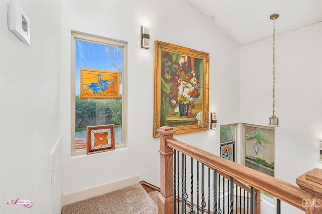 hall featuring lofted ceiling, an upstairs landing, and baseboards