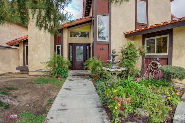 entrance to property with a tiled roof and stucco siding