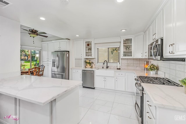 kitchen featuring stainless steel appliances, visible vents, white cabinetry, decorative backsplash, and glass insert cabinets