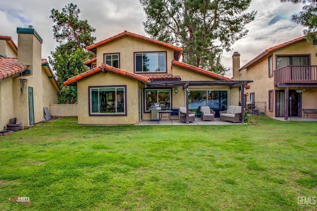 rear view of house with a patio area, a tile roof, outdoor lounge area, and a lawn