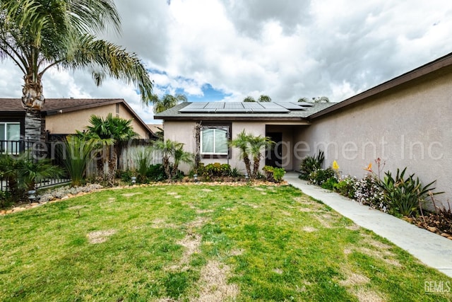 view of front of property with a front lawn and solar panels