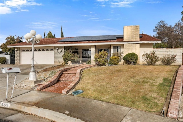 ranch-style home featuring a garage, a front yard, solar panels, and a porch