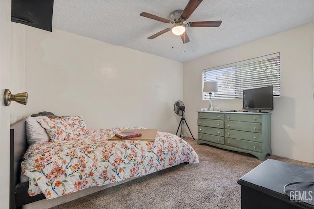 bedroom with ceiling fan, carpet floors, and a textured ceiling