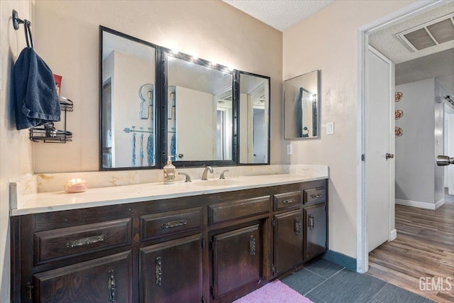 bathroom featuring vanity, wood-type flooring, and a textured ceiling