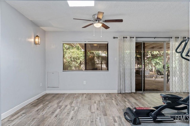 exercise room featuring hardwood / wood-style flooring, ceiling fan, a healthy amount of sunlight, and a textured ceiling