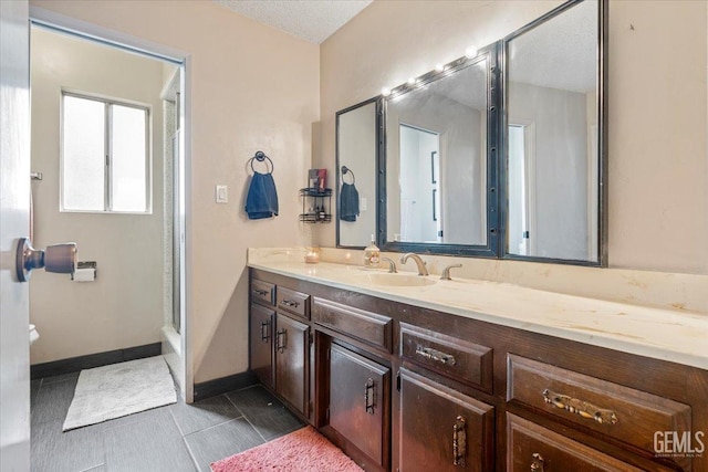 bathroom with vanity, a shower, and a textured ceiling