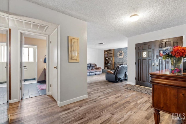 entrance foyer featuring a textured ceiling, light hardwood / wood-style floors, and a fireplace