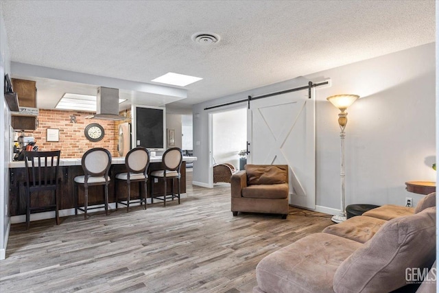 living room with light hardwood / wood-style flooring, a barn door, and a textured ceiling