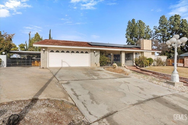 ranch-style house with a garage and solar panels