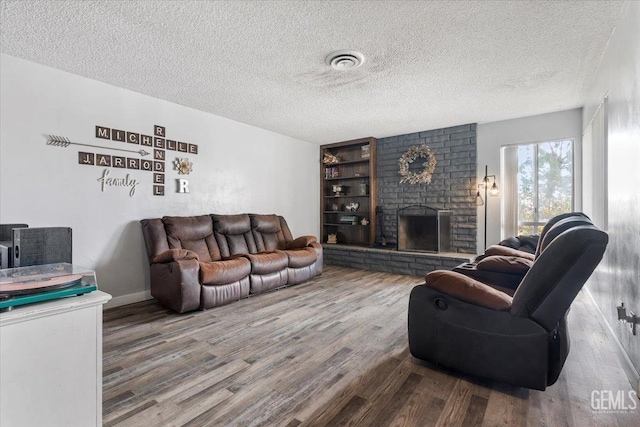 living room featuring hardwood / wood-style floors, a textured ceiling, and a fireplace