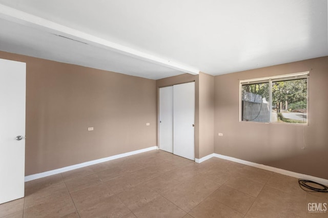 unfurnished bedroom with baseboards, tile patterned floors, and a closet