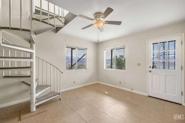 foyer entrance with stairway, tile patterned floors, baseboards, and a ceiling fan