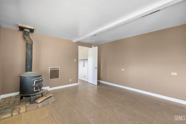 unfurnished living room featuring a wood stove, tile patterned floors, baseboards, and heating unit