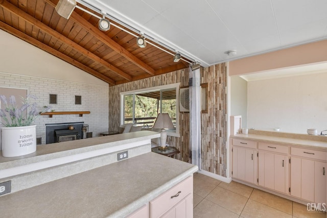 kitchen with lofted ceiling with beams, light tile patterned floors, brick wall, light countertops, and wooden ceiling