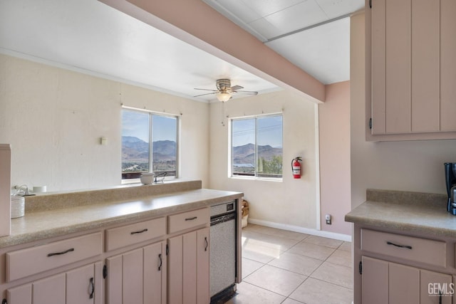 kitchen featuring light countertops, a ceiling fan, light tile patterned flooring, a mountain view, and baseboards