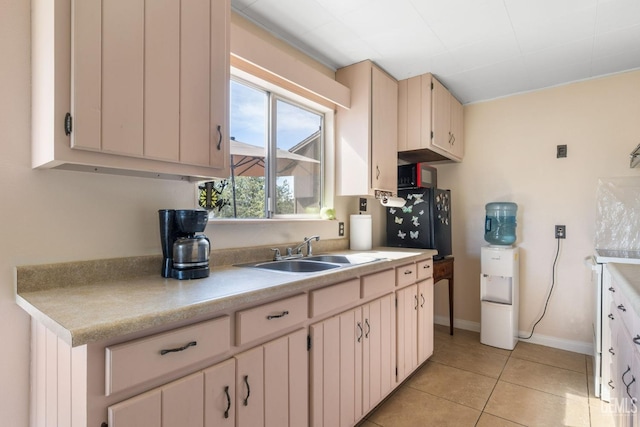 kitchen with baseboards, light tile patterned flooring, a sink, and light countertops
