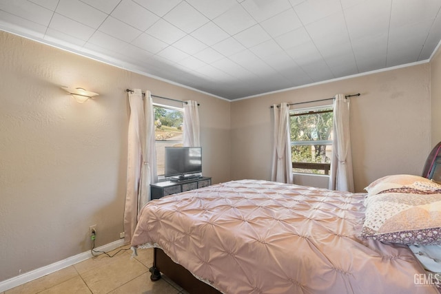 bedroom with baseboards, light tile patterned flooring, and crown molding