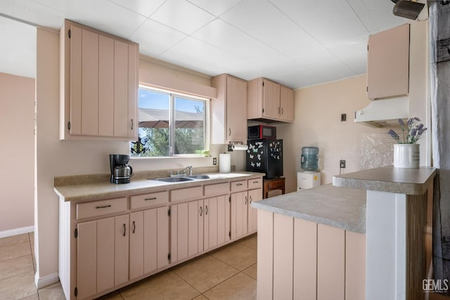 kitchen with a peninsula, a sink, light countertops, light tile patterned floors, and cream cabinets