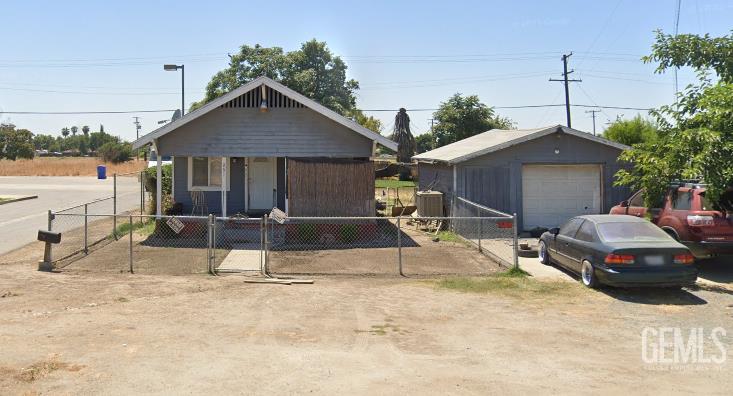 251 N Graham Rd, Tipton, CA 93272 - view of front facade featuring a garage, a fenced front yard, an outbuilding, a porch, and driveway