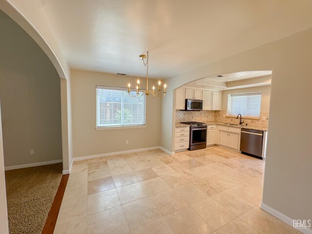 12301 Nacelle Ave, Bakersfield, CA 93312 - kitchen featuring appliances with stainless steel finishes, white cabinets, light stone countertops, arched walkways, and decorative backsplash
