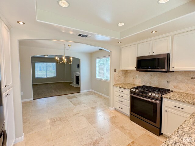 12301 Nacelle Ave, Bakersfield, CA 93312 - kitchen with stainless steel appliances, arched walkways, backsplash, white cabinets, and light stone countertops
