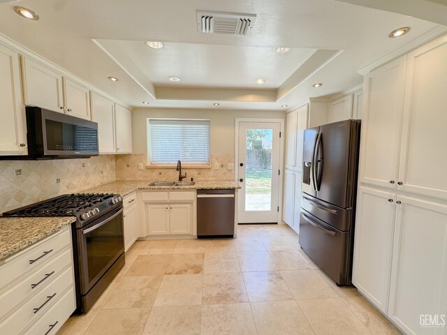 12301 Nacelle Ave, Bakersfield, CA 93312 - kitchen featuring stainless steel appliances, decorative backsplash, a raised ceiling, light stone countertops, and white cabinets