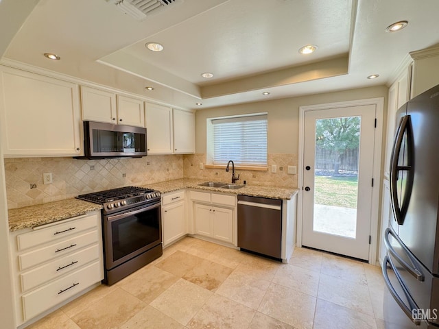 12301 Nacelle Ave, Bakersfield, CA 93312 - kitchen featuring appliances with stainless steel finishes, a tray ceiling, tasteful backsplash, light stone counters, and recessed lighting