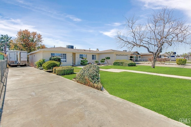 ranch-style house featuring driveway, an attached garage, and a front yard