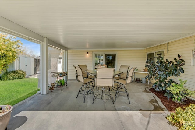 view of patio / terrace with outdoor dining area, a storage unit, and an outbuilding