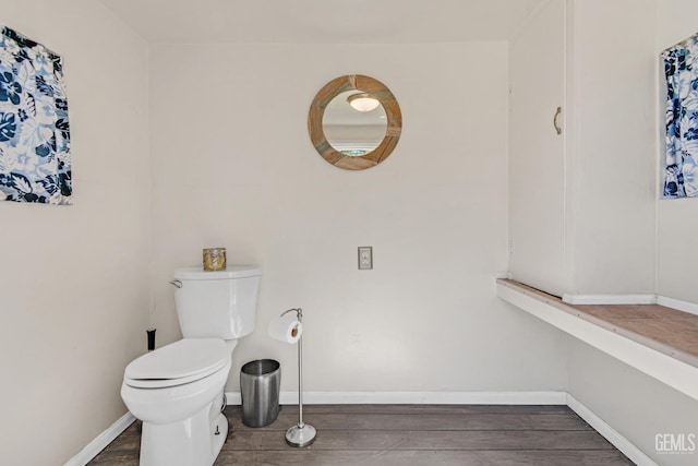 bathroom featuring toilet, baseboards, and wood finished floors