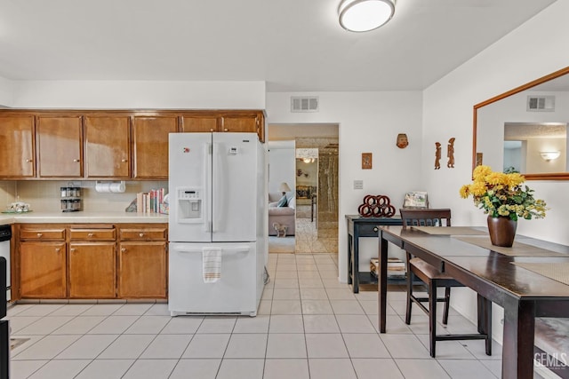 kitchen featuring visible vents, brown cabinets, and white refrigerator with ice dispenser