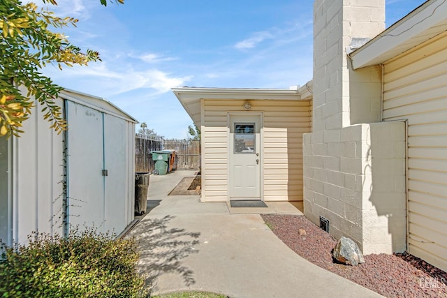 view of exterior entry featuring a patio area, concrete block siding, and fence