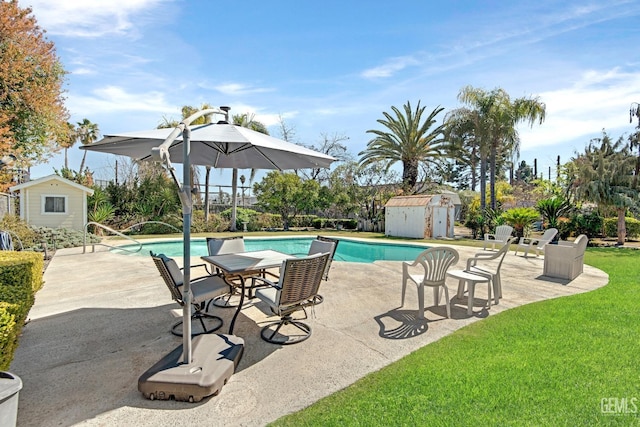 view of pool with an outbuilding, a patio, a yard, a storage shed, and a fenced in pool