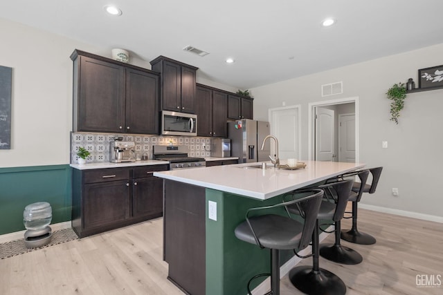 8610 Kowa St, Bakersfield, CA 93314 - kitchen featuring appliances with stainless steel finishes, light wood-style floors, a center island with sink, a breakfast bar, and recessed lighting