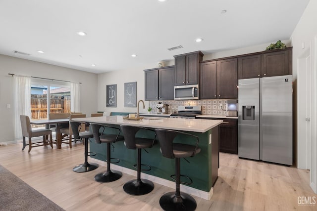8610 Kowa St, Bakersfield, CA 93314 - kitchen with appliances with stainless steel finishes, light countertops, dark brown cabinetry, a center island with sink, and a breakfast bar
