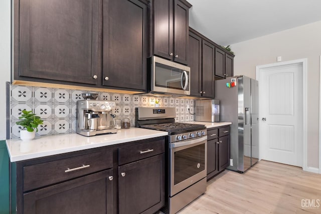 8610 Kowa St, Bakersfield, CA 93314 - kitchen with stainless steel appliances, tasteful backsplash, dark brown cabinetry, light wood-type flooring, and light countertops