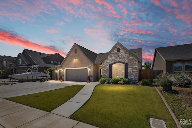 french country inspired facade with stone siding, a garage, concrete driveway, and stucco siding