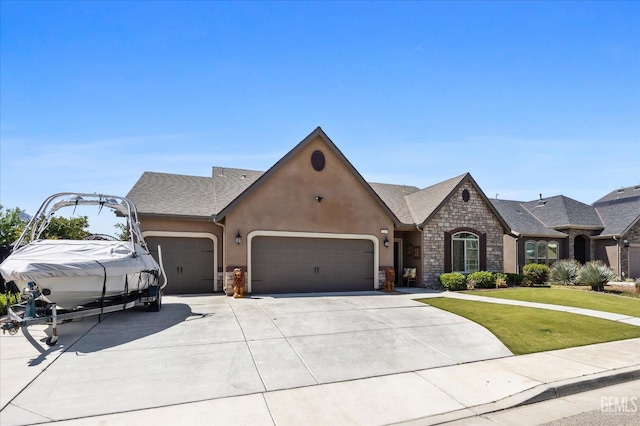 french country inspired facade with an attached garage, stone siding, concrete driveway, a front lawn, and stucco siding